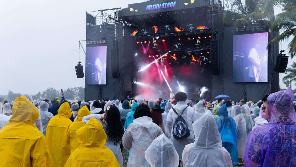 Asistentes con capas para lluvia observan el escenario Mishu en Isle of Light 2026